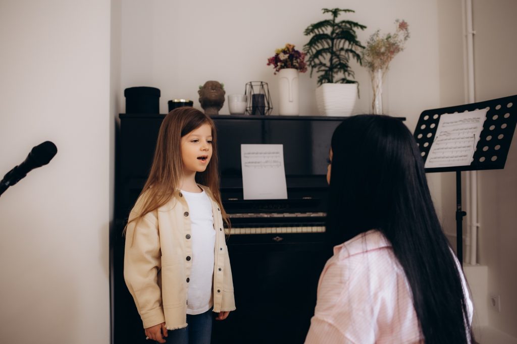 A little girl learns to sing at vocal lessons